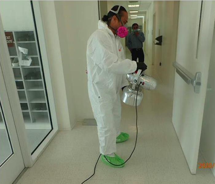 Team member in PPE and disinfecting. 